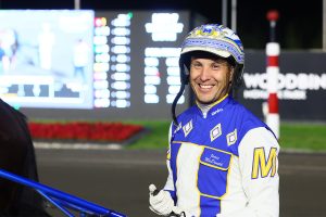Smiling harness racing driver James MacDonald in blue and white racing silks at Woodbine Mohawk Park